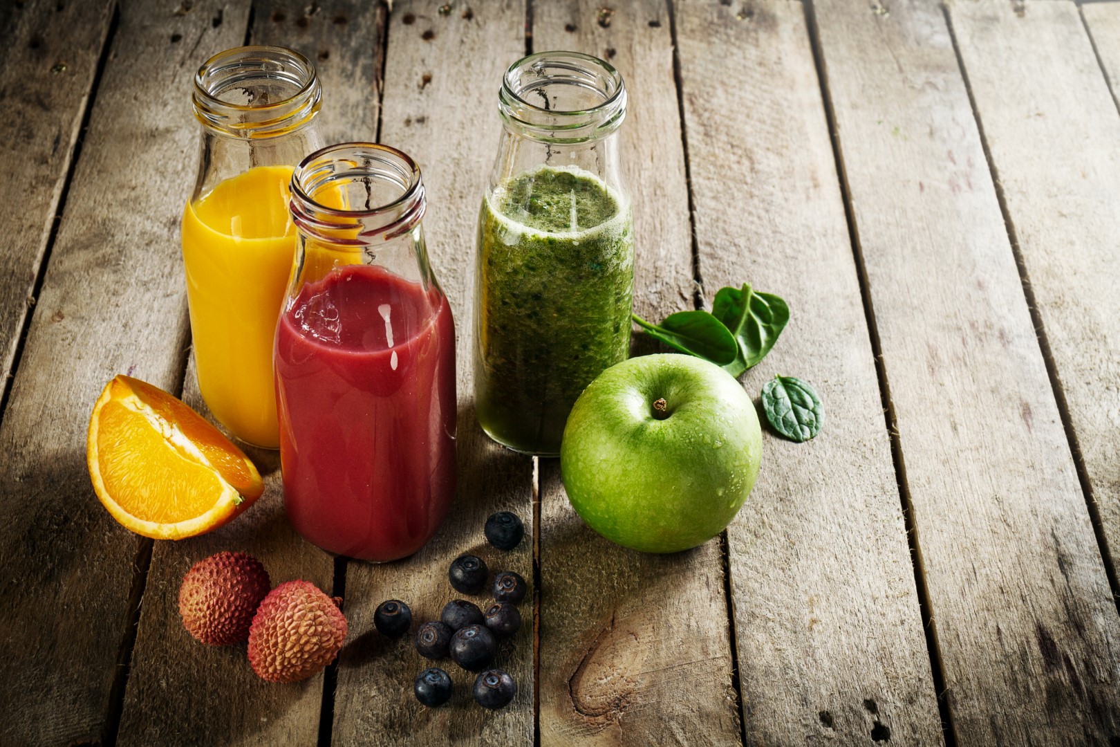 Tasty colorful fresh homemade smoothies in glass jars on wooden